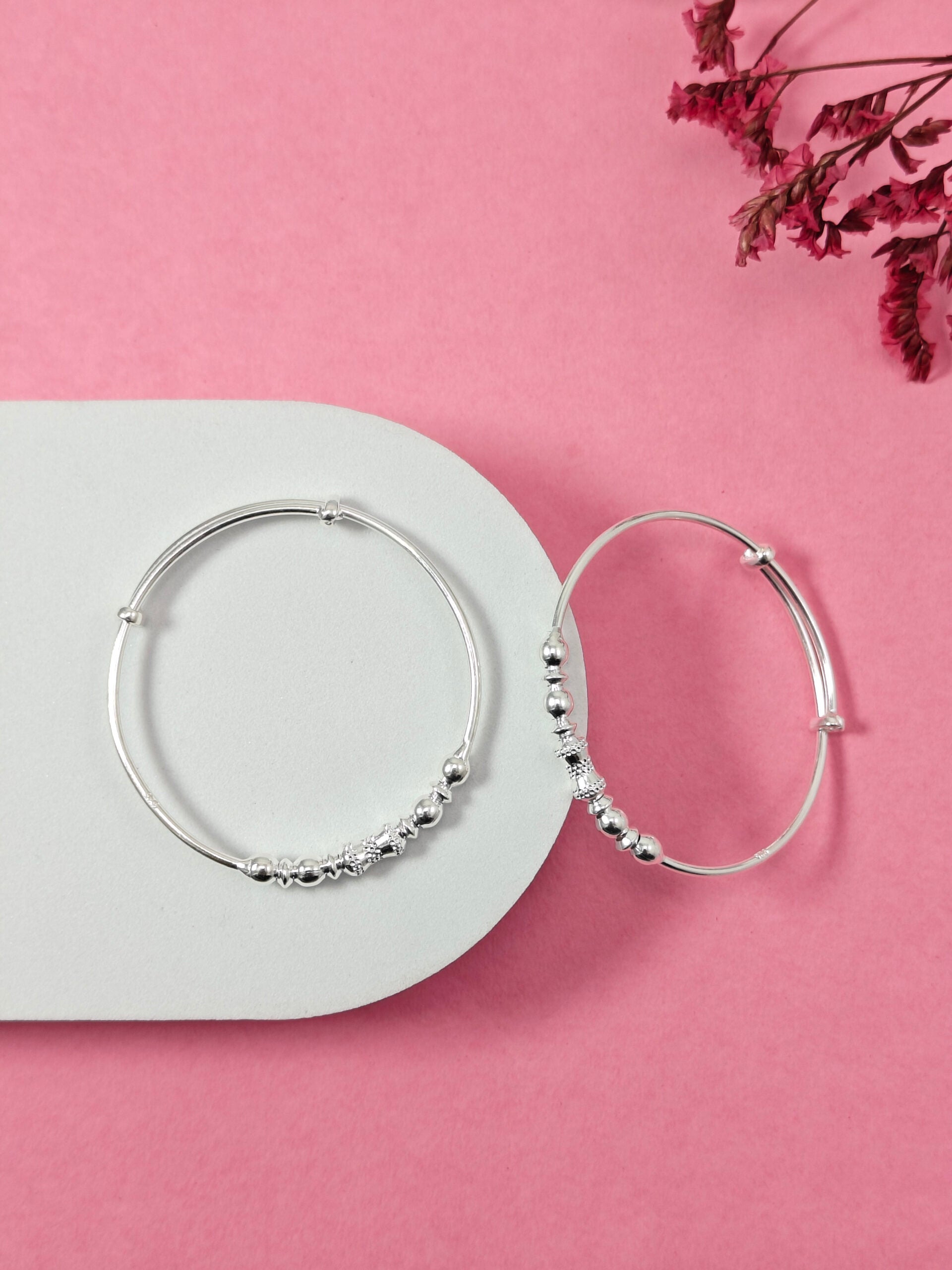 Silver hoop earrings on a pink background with dried flowers.